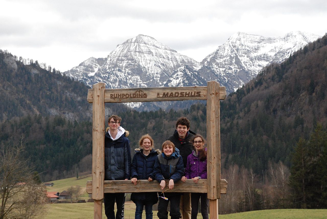 Vor einem schönen Bergpanorama steht ein hölzerner Rahmen. Darauf steht „Ruhpolding Madshus“. Im Rahmen stehen Florian, Lara, Christopher, Julian und Marija. Sie lächeln in die Kamera.