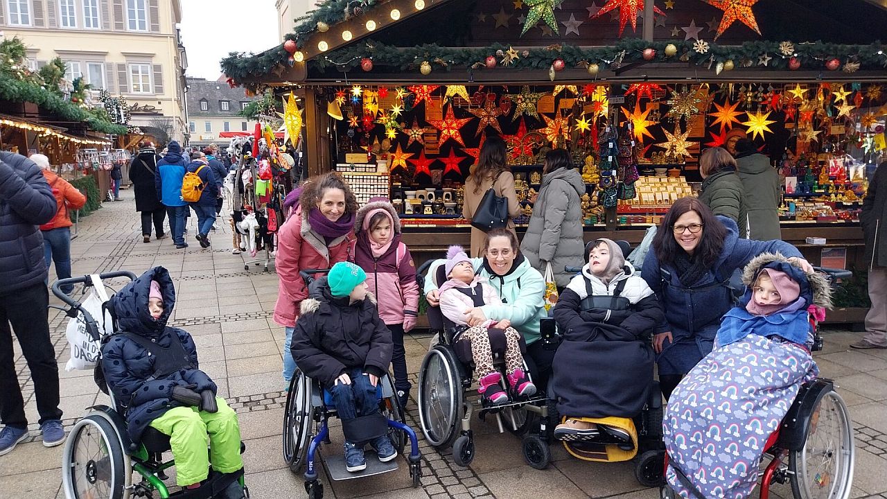Die Schülerinnen und Schüler der Klasse 3a stehen vor einem Weihnachtsmarktstand, der Sterne zum Verkauf anbietet.