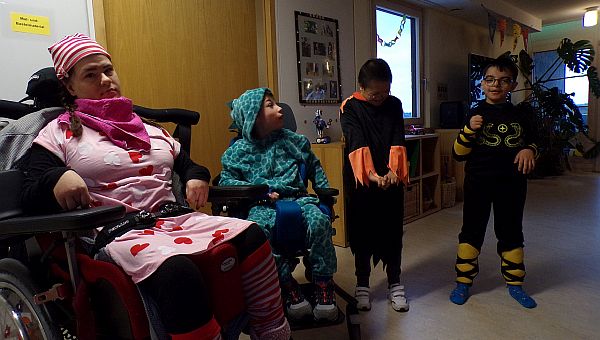 Es sind 4 Kinder zu sehen. Links ein Mädchen verkleidet als Schlafmütze im Schlafanzug. Daneben ein Junge in grünem Dinosaurierkostüm. 
