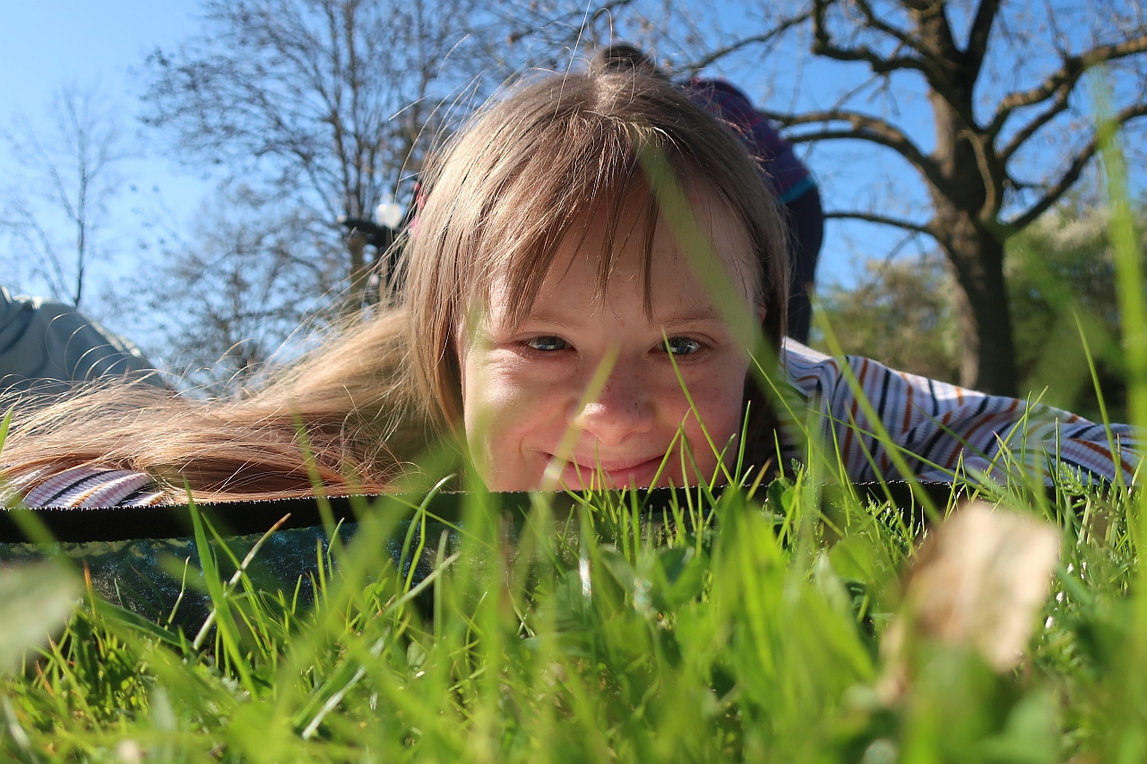 Eine Schülerin liegt im Gras und schaut in die Kamera.