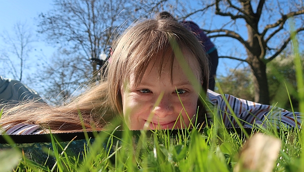 Eine Schülerin liegt im Gras und schaut in die Kamera.