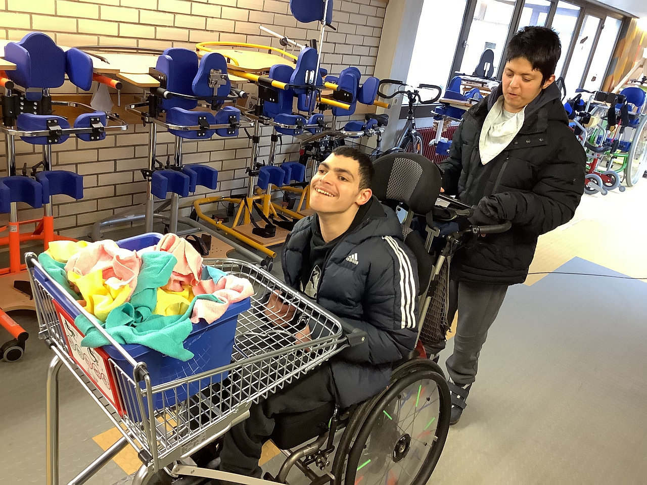 2 Schüler fahren mit einem Wagen Lappen durch einen Flur.