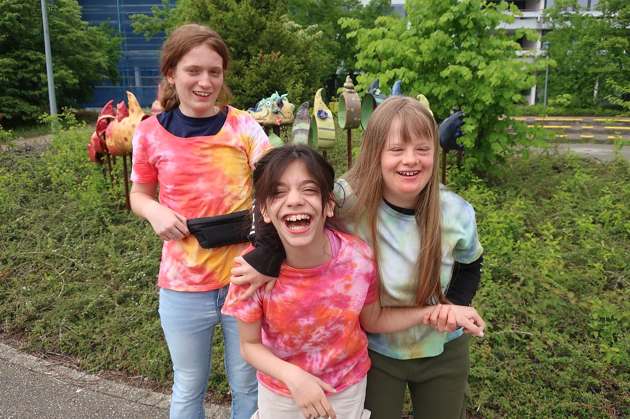 Drei Mädchen strahlen mit ihren frisch gebatikten T-Shirts in die Kamera