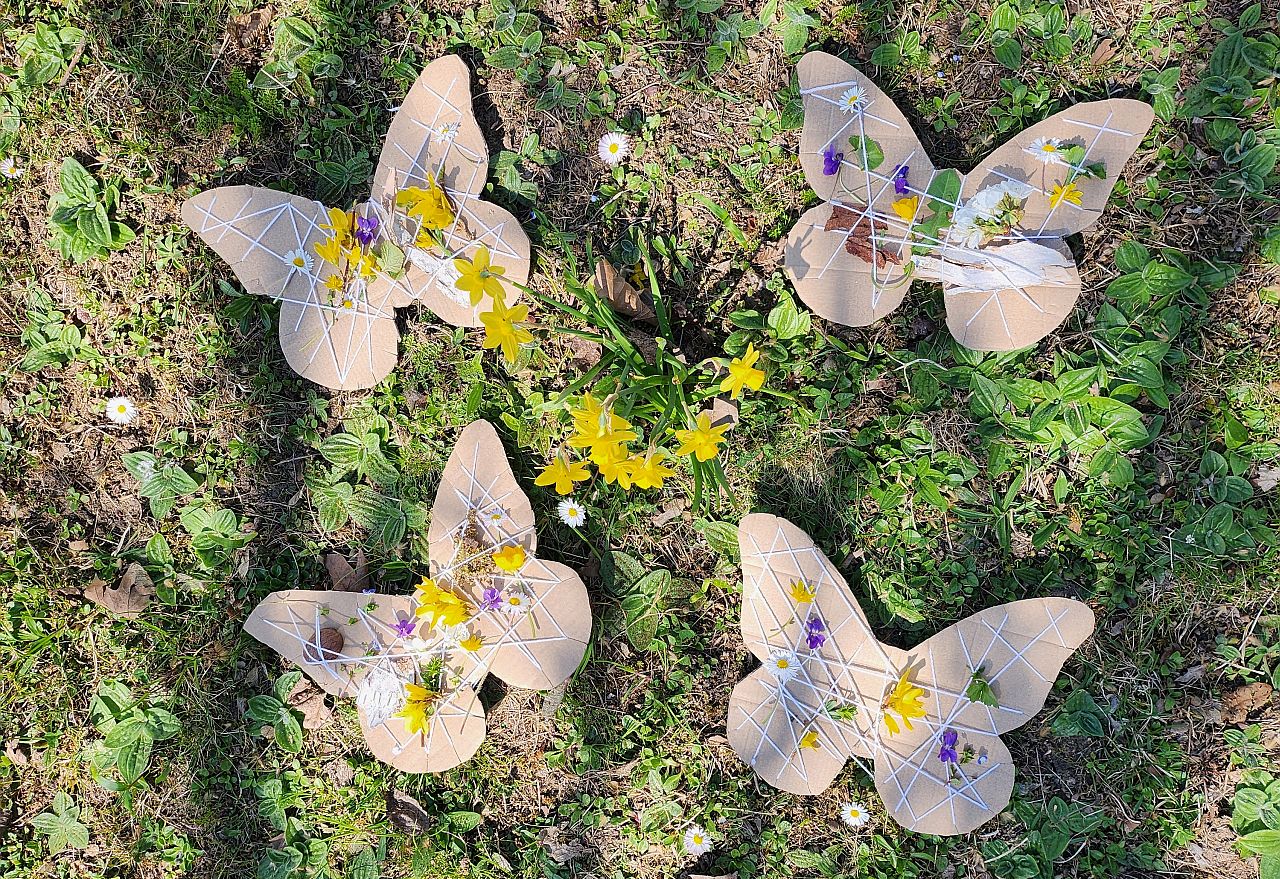 4 Schmetterlinge aus Pappe geschnitten, Schnur drumgebunden, um verschiedenfarbige Blumen, Blätter rein zu stecken. 