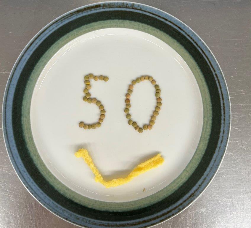 Auf einem Teller ist aus Linsen die Zahl 50 gelegt, darunter aus Spätzle ein Mund, es sieht aus wie ein Smiley