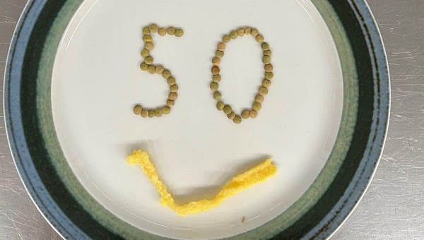 Auf einem Teller ist aus Linsen die Zahl 50 gelegt, darunter aus Spätzle ein Mund, es sieht aus wie ein Smiley