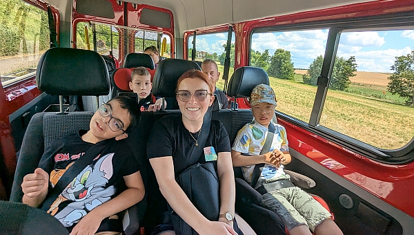 Eine Gruppe von Schülern und Schülerinnen sitzen zusammen mit zwei Betreuern in einem Bus.  