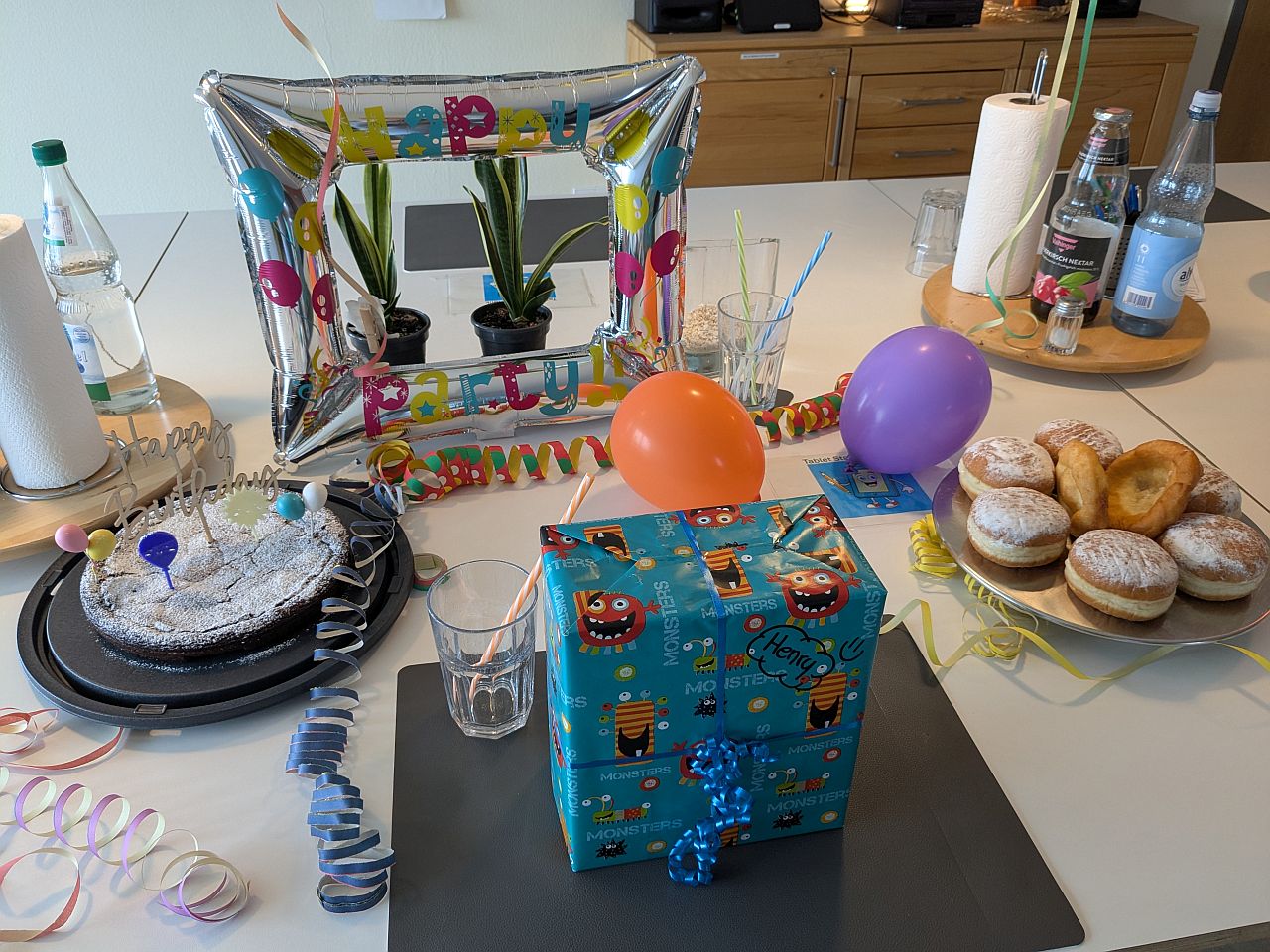 Ein geschmückter Tisch mit einem Geschenk, Luftballons, Luftschlangen und Kuchen :) 