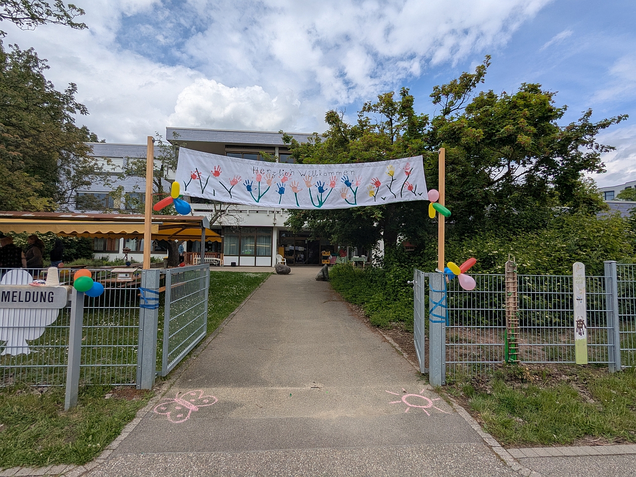 Eingangstor zum Fest mit einem bunten Banner Herzlich Willkommen mit Luftballons