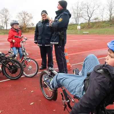 Zwei Polizisten sprechen mit Schülern auf ihren Fahrrädern.