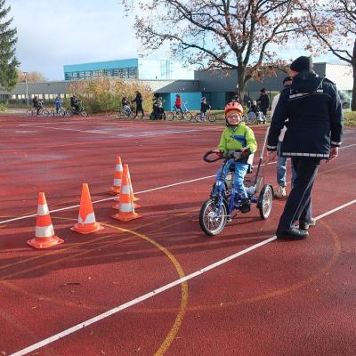 Polizist zeigt einem Schüler vor dem Hindernis, wie der Schulterblick geht.