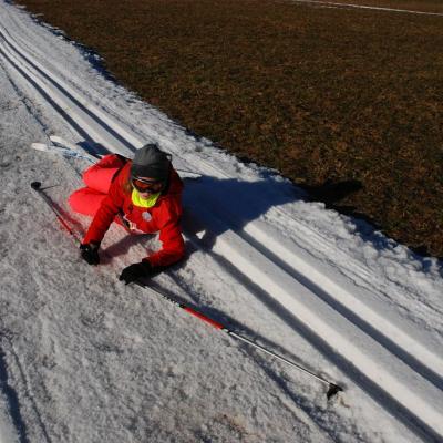 Lara liegt seitlich auf der Loipe und schaut in die Kamera.