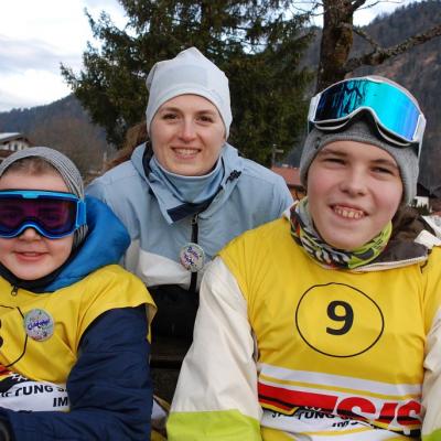 Christopher, Frau Fecke und Julian sitzen auf einer Bank und lächeln in die Kamera.