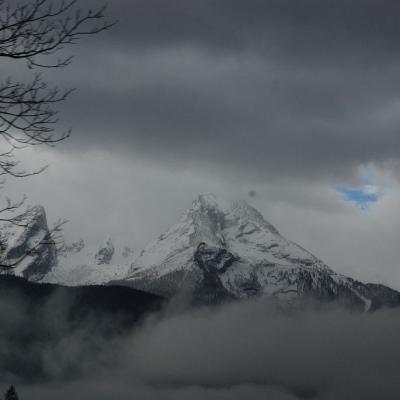 Man sieht eine Bergkette mit weißen Gipfeln. Der Himmel ist mit grauen Wolken verhangen.