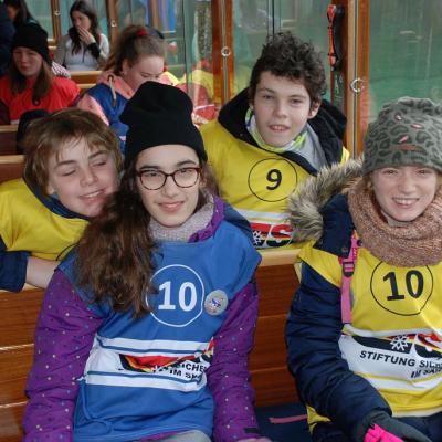 Christopher, Marija, Julian und Lara sitzen auf den Bänken im Boot und lächeln in die Kamera.