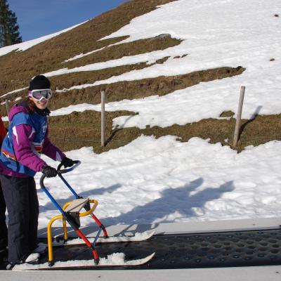 Marija und Martin von der Skiwacht stehen auf einem Förderband, das sie nach oben befördert.