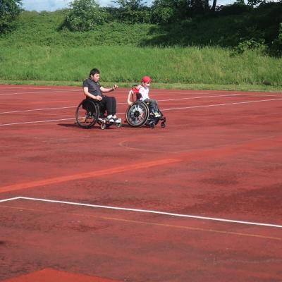 Zwei Rollstuhlfahrer fahren über das Fußballfeld.