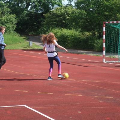 Ein Mädchen will gerade den Ball ins Tor schießen.