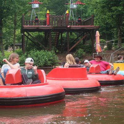 Auf einem kleinen See schwimmen drei rote Boxauto-Boote mit jeweils einem Schüler und einem Betreuer