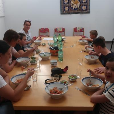 Schüler und Betreuer sitzen um den Essenstisch herum und essen Spaghetti
