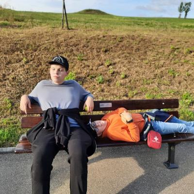 Zwei Schüler ruhen sich in der Sonne auf einer Bank aus
