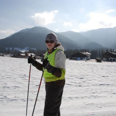 Julian steht in der Loipe und lächelt in die Kamera. Im Hintergrund sieht man ein großes Schneefeld und die schöne Landschaft mit dem guten Wetter.