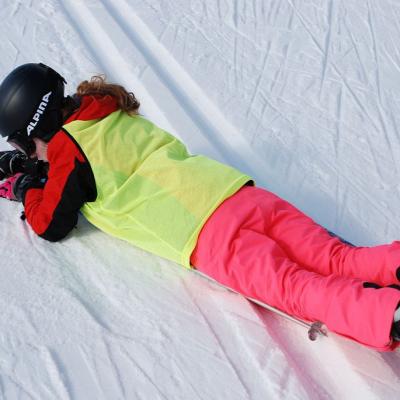 Lara liegt kerzengerade auf ihren Skiern quer über die Loipe. Es sieht aus, als wäre sie gestürzt.