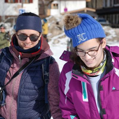 Frau Wörner von Stuttgart und Marija laufen nebeneinander und lächeln. Beide schauen nach unten auf Marijas Skilator.