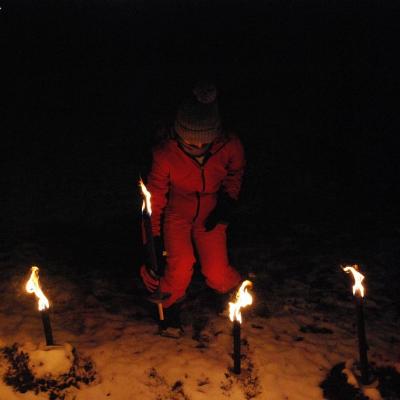 Lara steckt ihr Fackel in den Schneeberg. Um sie herum stecken vier weitere Fackeln.