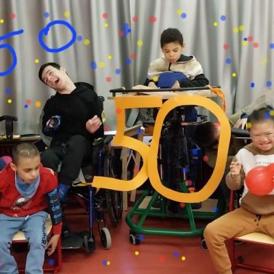 Eine bunt gemischte kleine Schulklasse mit einem gro0ßen gelben Schriftzug 50.