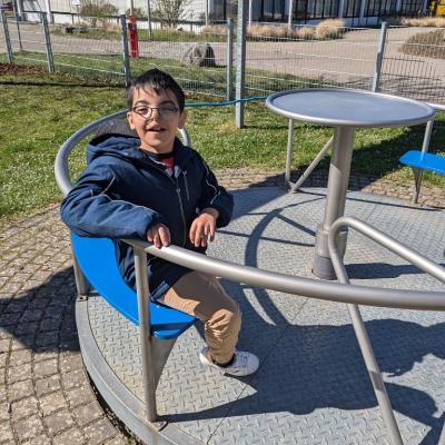 Ein Junge sitzt in einem Karussell. Er schaut lächelnd in die Kamera 
