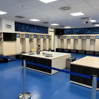 Auf dem Bild ist die  Umkleidekabine der TSG Hoffenheim. Jeder Spieler hat seinen eigenen Platz und in der MiIe steht Tee für alle.