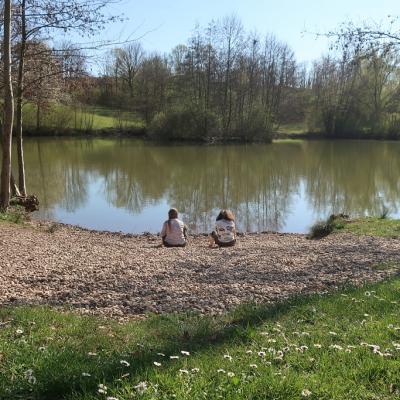 Zwei Mädchen sitzen am Ufer eines Sees.