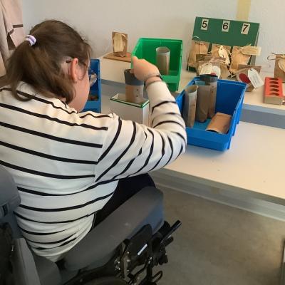 Eine Schülerin sitzt an einem Tisch und verpackt Samenbomben.