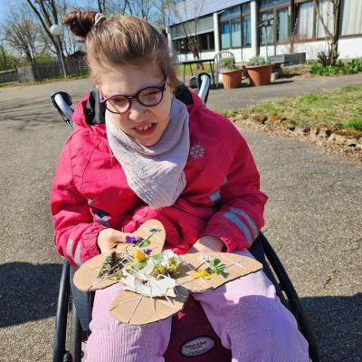 Rollstuhlfahrerin mit pink färbende Jacke , hält ihren Schmetterling aus Pappe fest 