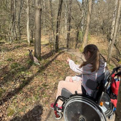 Schülerin im Rollstuhl zeigt auf den gefunden Hasen im Wald