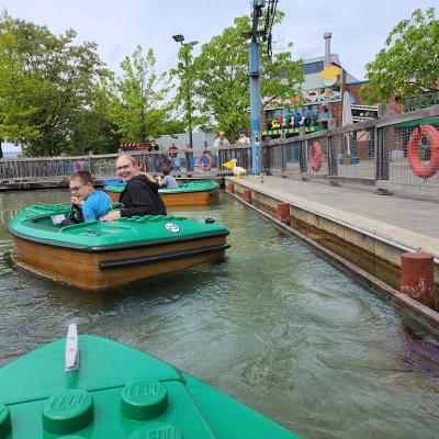 Eine Frau und ein Junge sitzen in einem Legoboot. Das Boot schwimmt auf dem Wasser 