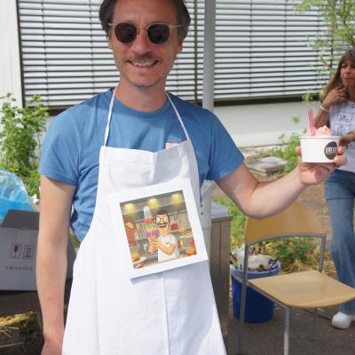 Ein Lehrer mit einer Schürze und einem kleinen Eisbecher in der Hand
