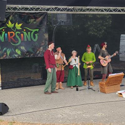 Eine Band aus 5 Personen, 4 Männer und eine Frau , tragen alle mittelalterliche Kleidung und Mittelalterlicher Instrumente
