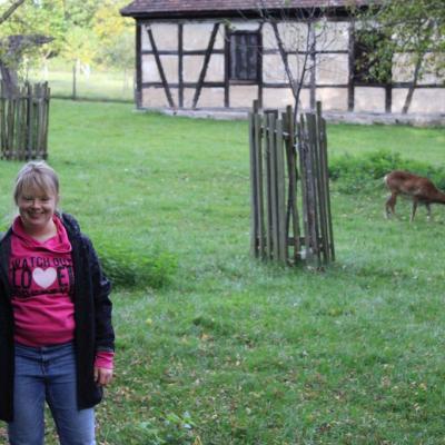 Eine junge Frau lacht in die Kamera, im Hintergrund grast ein Wildtier