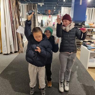 Zwei Jungen und ein Mädchen stehen in einem Einkaufszentrum.Sie haben sich Gläser ausgesucht.Jetzt halten sie die Gläser hoch.Sie sind stolz auf ihre Auswahl.
