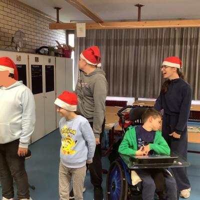 Auf dem Foto sind drei Schüler und 2 Schülerinnen zu sehen die Weihnachtsmützen tragen. Sie haben gemeinsam den Kopf nach rechts gedreht.