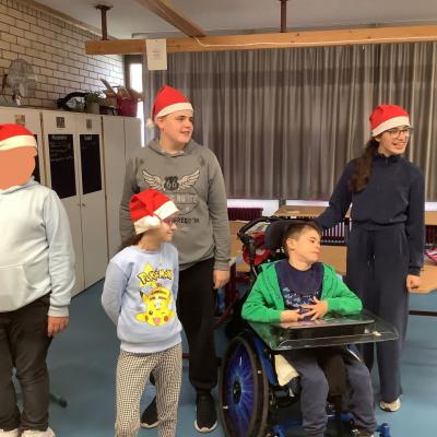 Auf dem Foto sind drei Schüler und 2 Schülerinnen zu sehen die Weihnachtsmützen tragen. Sie haben gemeinsam den Kopf nach links gedreht.