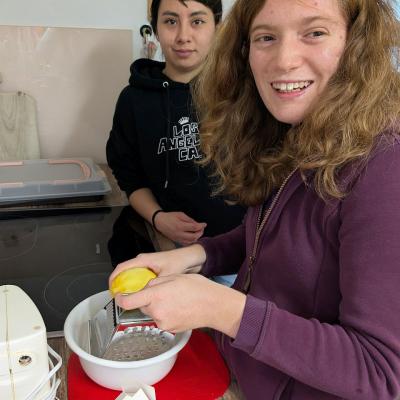 Ein Mädchen und Mitarbeiterin stehen in der Küche und raspeln eine Zitrone