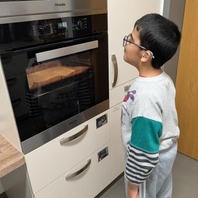 Ein Junge steht vor dem Backofen und schaut nach dem Kuchen 