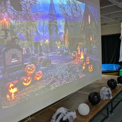 Ein Geist hängt neben einer Leinwand auf dieser eine gruselige und gespenstige Halloween-Landschaft geziet wird