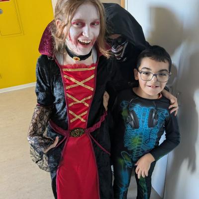 Ein Mädchen im Vampirkostüm und ein Junge mit einem Skelettkostüm stehen nebeneinander und lächeln in die Kamera