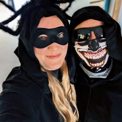 Zwei kostümierte Frauen, eine als Spinne, die andere als Geist, lächeln in die Kamera