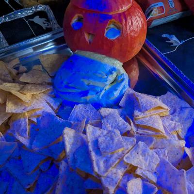 Eine große Platte mit Nachos und einem Kürbis stehen am Buffet, der Kürbis wurde mit einem Dip gefüllt und muss sich übergeben