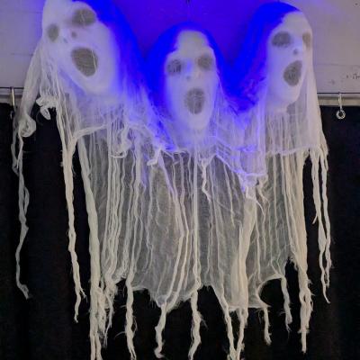 Eine Dekoration hängt an der Wand. Drei gruselige Köpfe mit blauen Licht